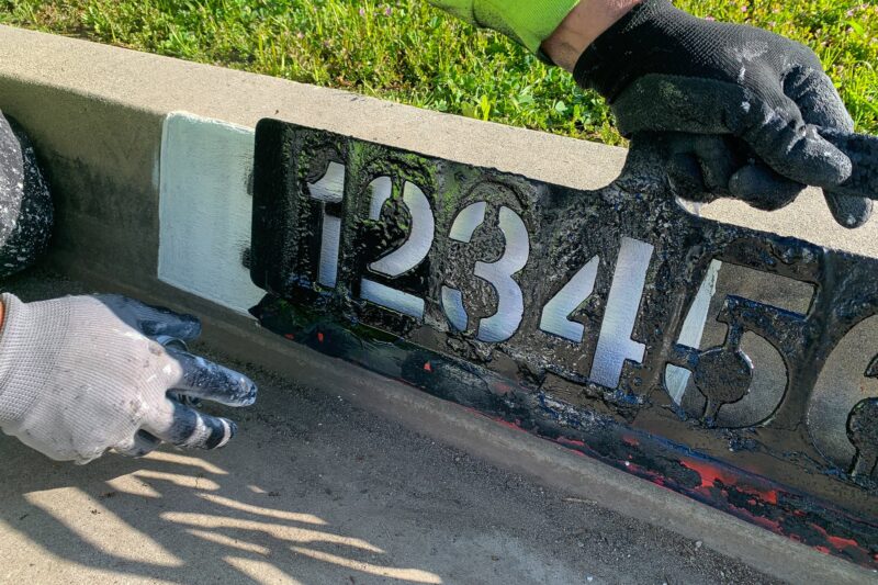 Close-up of stenciled address numbers on a street curb