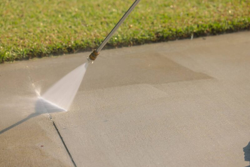 High-pressure water stream cleaning a patio surface